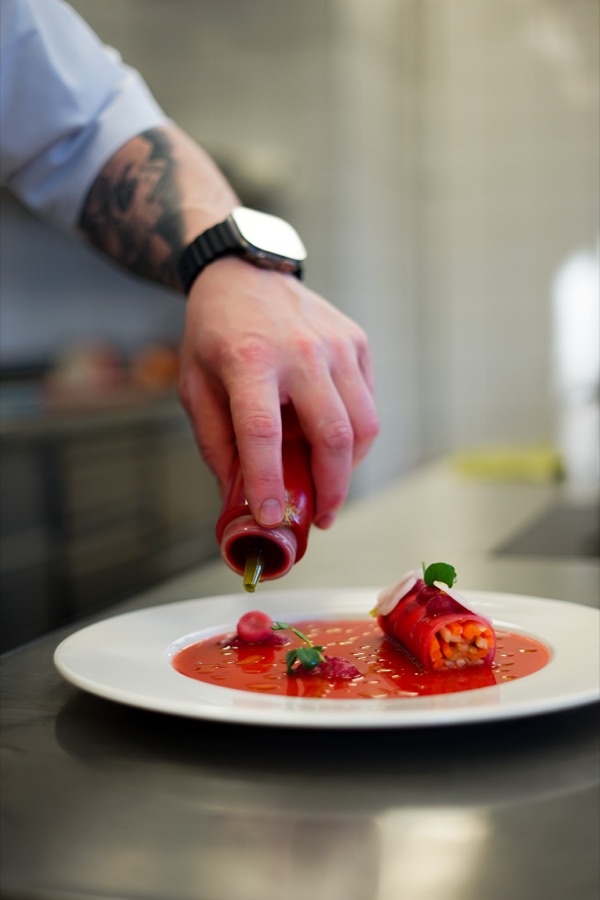 Anatols Hand beim Anrichten eines Tellers mit roter Sauce
