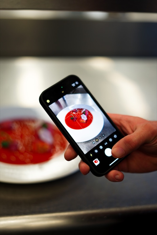 Hand mit Handy, das einen Teller fotografiert